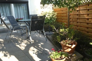 An outdoor seating area with a table and chairs, surrounded by potted plants and a wooden fence. - Heinisch family with pool (Ringenhain)