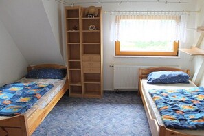 A bedroom with two single beds, a built-in wardrobe, a radiator, and a window with curtains. - Holiday home with 1 bedroom (Markersbach \/ Bad Gottleuba-Berggießhübel)