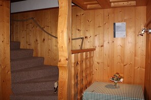 A wooden interior with a carpeted staircase, a small table with a checkered tablecloth, and a wall-mounted sign. - Holiday home with 1 bedroom (Markersbach \/ Bad Gottleuba-Berggießhübel)