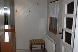 A hallway with a wooden bench, a white door with a window, and a radiator. - Holiday home with 1 bedroom (Markersbach \/ Bad Gottleuba-Berggießhübel)