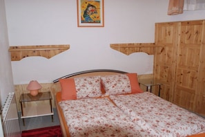 A bed with a floral bedspread, a bedside lamp, and a wooden headboard. - Holiday apartment with 2 bedrooms (Bodensdorf)