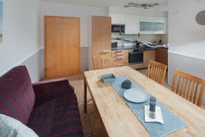 A compact living space with a dining area, kitchenette, and a wooden door. - The house at the southern end of the spa park (Norderney)