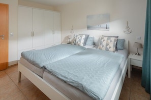 Ein Schlafzimmer mit einem Bett, einem Kleiderschrank, einem Nachttisch und einer Wandlampe.
