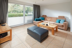 A modern living room with a sofa, ottoman, and coffee table. - The house at the southern end of the spa park (Norderney)