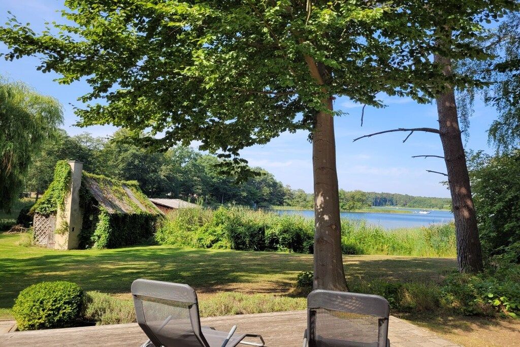A serene outdoor seating area with two chairs, a wooden deck, and a view of a lake.