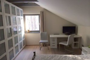 A bedroom with a bed, a desk, a chair, a television, and a window with curtains. - Holiday home with 3 bedrooms (Rheinsberg OT Zechlinerhütte)