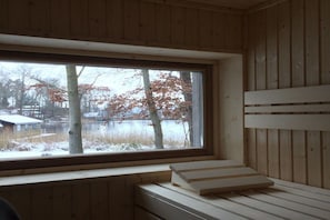 A room with a large window, wooden walls, and a bench. - Holiday home with 3 bedrooms (Rheinsberg OT Zechlinerhütte)