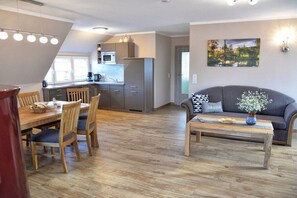 A modern living space with a dining area, a sofa, and a kitchen. - Holiday apartment with 1 bedroom (Lübbenau)