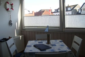 Ein kleiner Raum mit Tisch, Stühlen, einem Fenster und Blick auf Gebäude.