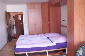 Ein Schlafzimmer mit einem Bett, einem Holzschrank und einer Tür zu einem anderen Raum.
