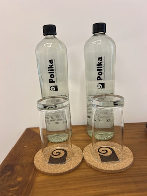 Two Polka water bottles and two clear glasses on coasters with a spiral design.