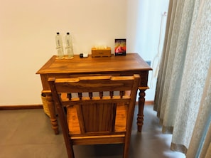 A wooden table with a chair in front, a small box, and two bottles on the table.