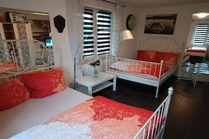 Een slaapkamer met een bed, nachtkastje, lamp en een raam met zonwering.
