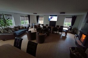 A spacious living area with a sofa, chairs, a dining table, and a fireplace. - Holiday home with 5 bedrooms (Ueckermünde)