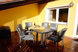 An outdoor dining area with a table and chairs, a window, and a tiled floor. - Holiday apartment with 2 bedrooms (Lübbenau)