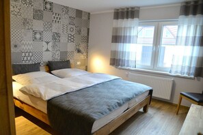 A bedroom with a bed, a radiator, a window with curtains, and a patterned wall. - Holiday apartment with 2 bedrooms (Lübbenau)