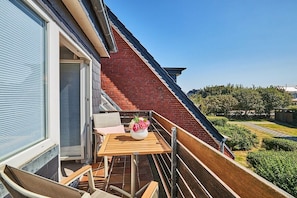 A balcony with a table and chairs, a flower vase, and a view of the surrounding area. - Holiday apartment with 2 bedrooms (Westerland)