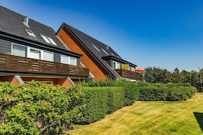 A row of modern houses with sloped roofs, wooden balconies, and a well-maintained lawn. - Holiday apartment with 2 bedrooms (Westerland)