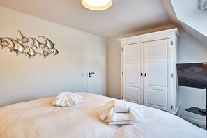 A hotel room with a bed, a wardrobe, a television, and a wall decoration. - Holiday apartment with 2 bedrooms (Westerland)