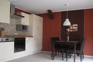 A modern kitchen with white cabinetry, a microwave, and a dining area with a table and chairs. - Holiday apartment with 3 bedrooms (Karlshagen)