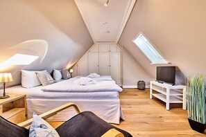 Une chambre à coucher avec un lit, une télévision, une plante et une fenêtre.