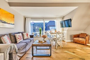 Un salon comprenant un canapé, une table basse et un coin repas avec des chaises et une table.