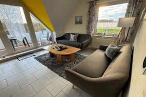 Una sala de estar con sofá, mesa de centro y vistas al exterior.