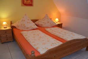 Ein Doppelbett mit floralem Bettbezug, zwei Nachttischlampen und ein hölzernes Kopfende.