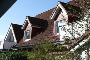 Un edificio residencial con techo a dos aguas, ventanas de tejado y chimenea visible.