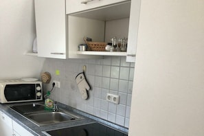 Eine Küche mit Mikrowelle, Spüle und einer Topfhalterung.