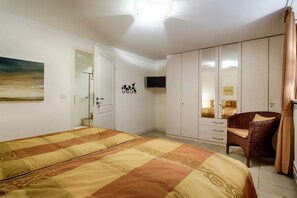 A bedroom with a bed, a wardrobe, a chair, and a television. - Holiday home in Sylt with 3 bedrooms (Wenningstedt)