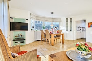 A modern living room with a television, dining area, and kitchen. - Holiday home in Sylt with 3 bedrooms (Wenningstedt)