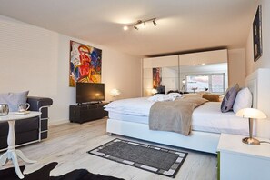 Un dormitorio moderno con cama, mesita de noche, lámpara y un espejo grande.