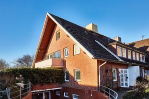 A two-story residential building with a sloped roof, a visible chimney, and a small balcony. - Holiday apartment in Sylt with 3 bedrooms (Westerland)