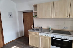 A kitchen with wooden cabinets, a built-in oven, a sink, and a countertop. - Holiday apartment Hilmersdorf (Hilmersdorf)