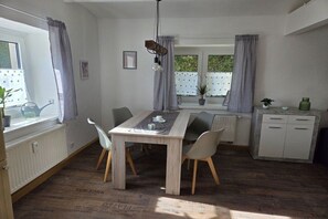 A dining area with a table, chairs, a hanging light fixture, and a view of the outdoors. - Holiday apartment Hilmersdorf (Hilmersdorf)