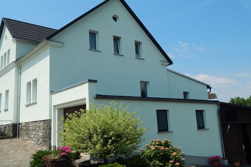A two-story building with a gabled roof, multiple windows, and a stone foundation.