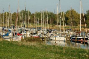 A marina with multiple boats docked, surrounded by greenery. - Holiday home in Hooksiel with swimming pool (Hooksiel)