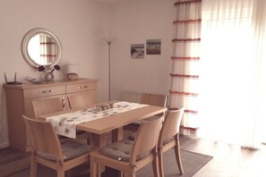 A dining area with a wooden table, chairs, a mirror, a lamp, and a radiator. - Holiday home in Hooksiel with swimming pool (Hooksiel)