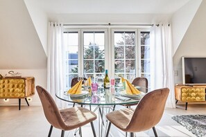 A dining area with a glass table, two chairs, and a bottle of wine. - Holiday apartment with 3 bedrooms (Westerland)