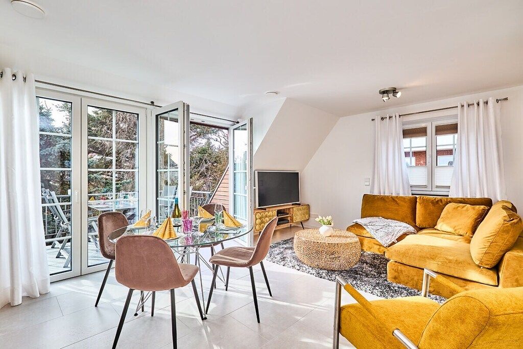 A modern living room with a glass dining table, comfortable seating, a flat-screen TV, and a sofa.