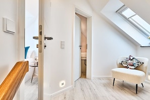 Ein modernes Interieur mit einem Oberlicht, einer weißen Tür und einem Sessel mit gemustertem Kissen.