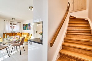 A modern interior with a dining area, a staircase, and a view into another room. - Holiday apartment with 3 bedrooms (Westerland)