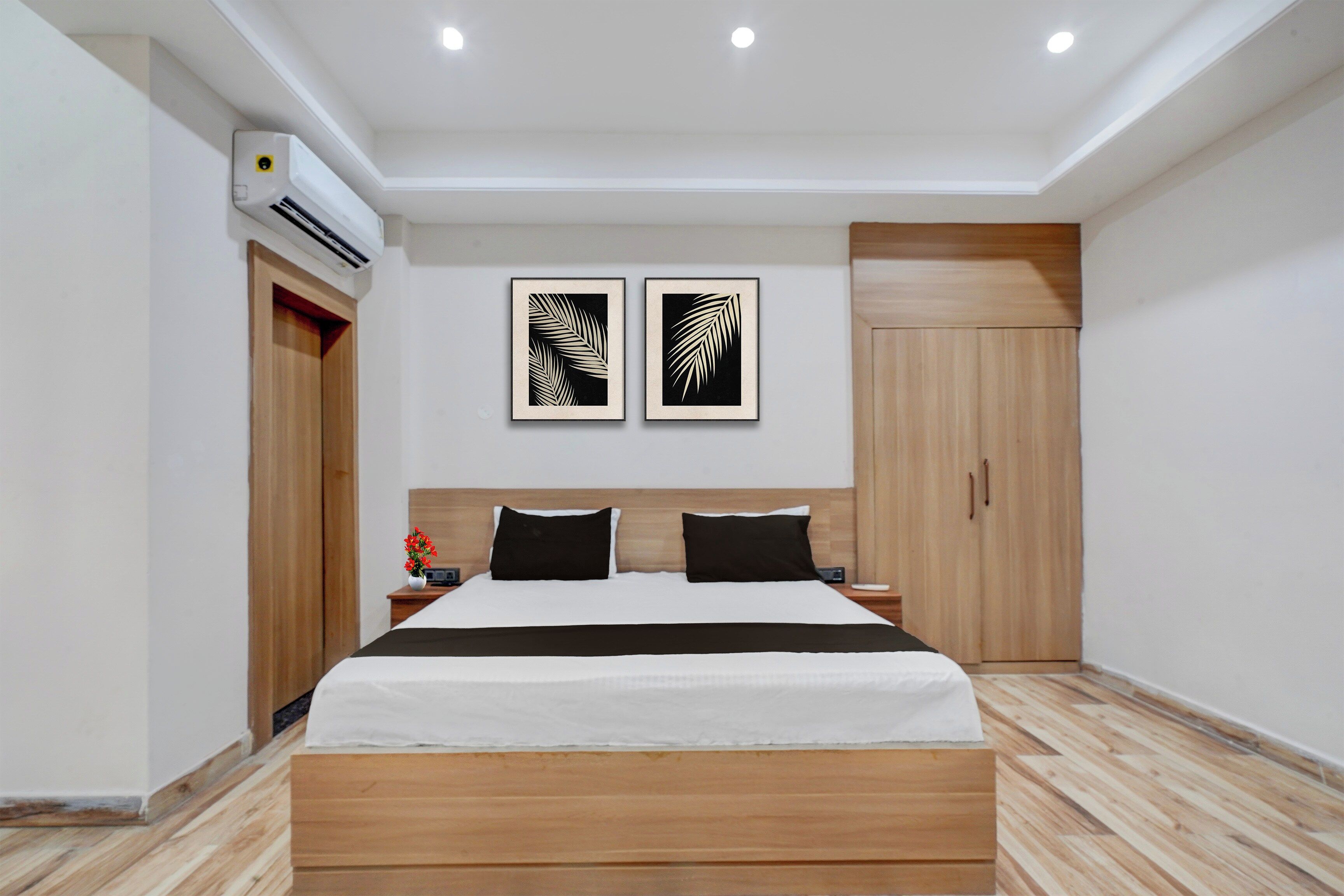 Un dormitorio moderno con una cama de madera, una mesita de noche, un armario y dos obras de arte con hojas enmarcadas en la pared.