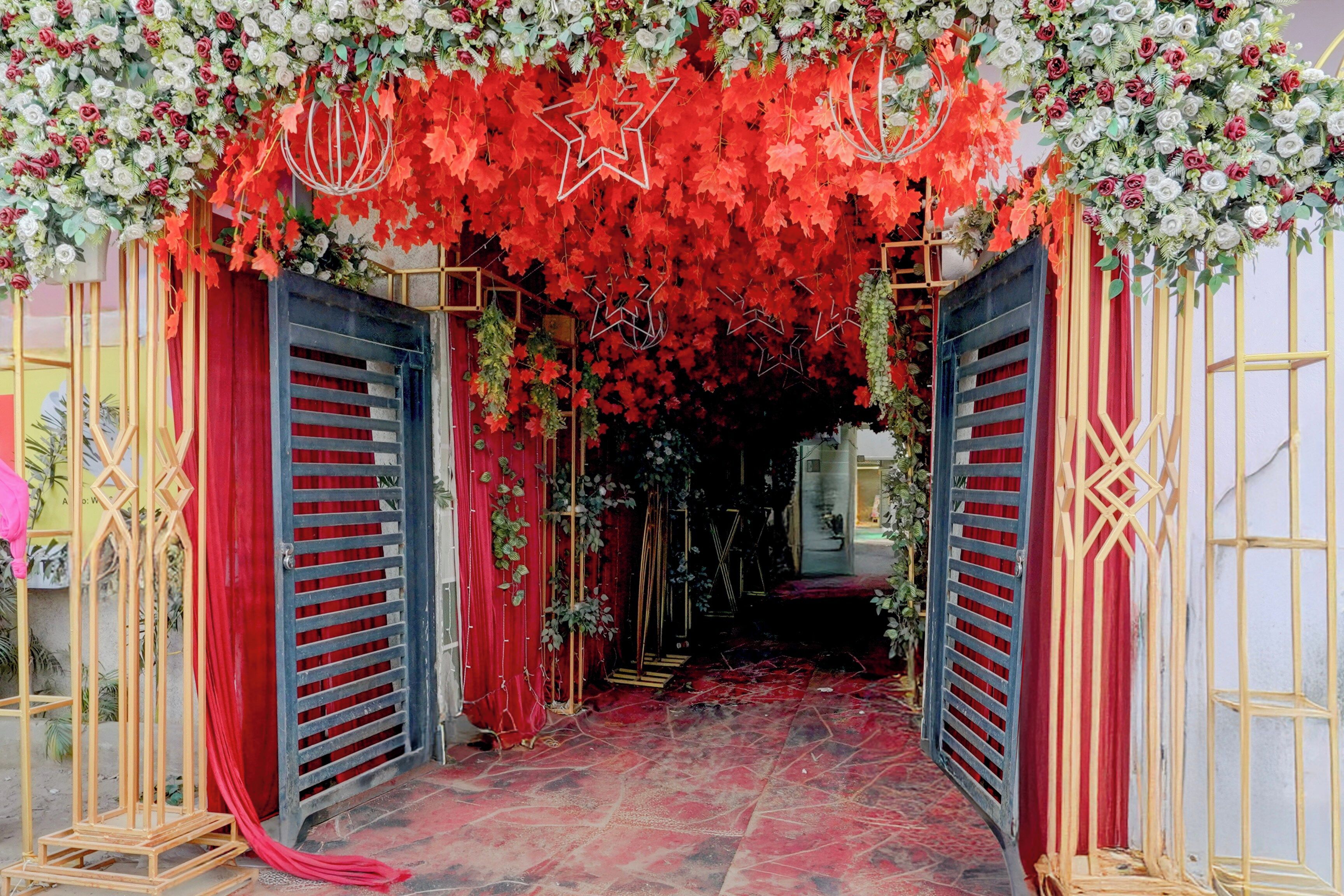 An entrance with red curtains and a floral archway.
