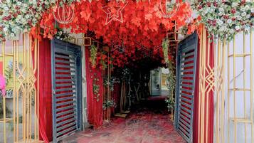 An entrance with red curtains and a floral archway.