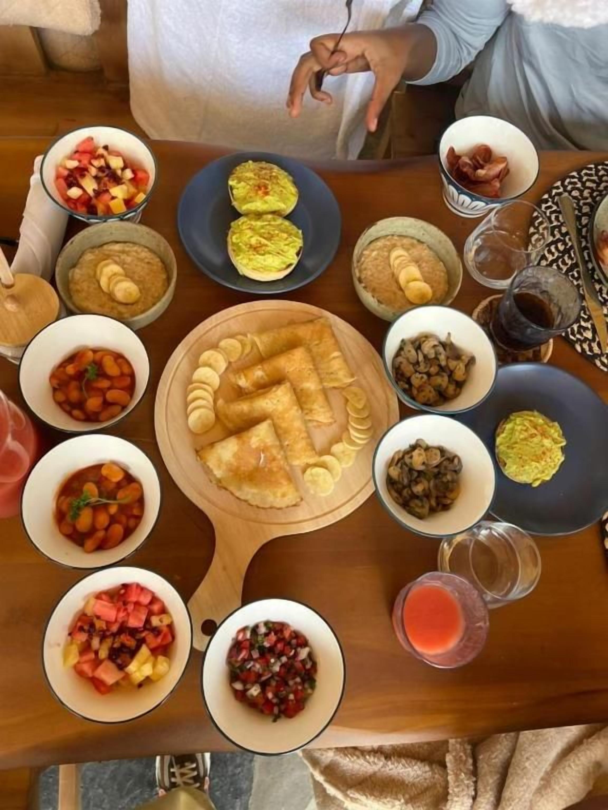 Una mesa con diversos platos y bebidas, incluyendo tazones de comida, un plato de pasteles y un vaso de bebida roja.