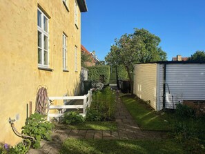 A residential property with a paved pathway, a white fence, and a garden area with various plants. - 1930s flat with a renovated garden in Valby (København)