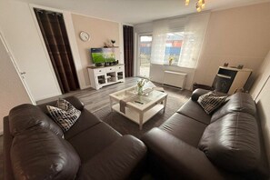 A living room with a sofa set, a coffee table, a television, and a fireplace. - Bungalow with 1 bedroom (Dornum - Dornumersiel)
