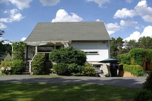 A two-story house with a covered porch, a garage, and a well-maintained lawn. - Holiday apartment with 1 bedroom (Himmelpfort)